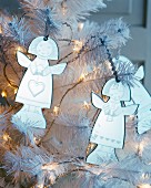 Angle decorations and fairy lights on white artificial Christmas tree