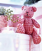 Red and white gingham teddy bear arranged on top of presents