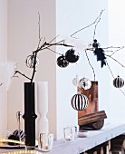 Elegant baubles and bird ornaments on bare branch in black vase