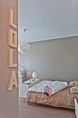Bedroom in soft beige shades with decorative letters on wall
