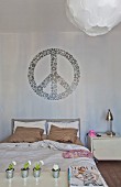 Peacezeichen als Wanddeko über dem Bett, Nachttisch aus Metall