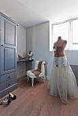 Tailors' dummy wearing underskirt in front of dressing table and easy chair