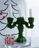 Candelabra covered in artificial pine needles and chocolate Father Christmases in glass dish