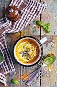 Cream of pumpkin soup with pumpkin seeds on a rustic wooden table