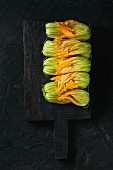 Courgette flowers on black chopping board