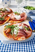Mini pizzas with ham, smoked salmon, prawns, rocket and yoghurt sauce