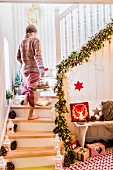Frau trägt Laterne auf weihnachtlich geschmückter Treppe