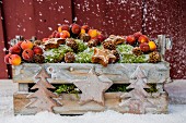 Snowy wooden create of moss, crab apples, pine cones and stars