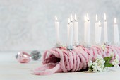 Small lit candles stuck in ball of pink wool