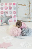 Balls of pastel wool in front of crocheted cushion cover