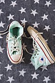 Pale green sneakers on grey rug with pattern of stars