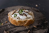 A slice of baguette topped with cream cheese, cress and crickets