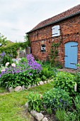 Brick house surrounded by cottage garden with stone-edged flowerbeds