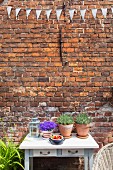 Potted plants on table below bunting on brick exterior wall