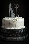 Zweistöckige Geburtstagstorte in Schwarz und Weiß dekoriert mit Damenschuh