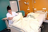 Nurse changing hospital bed linen