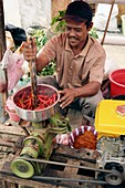 man grinding red chilies into powder