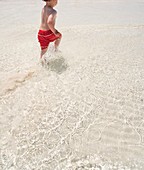 Young boy running through sea water