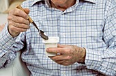 Elderly man eating a yoghurt