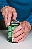 Elderly woman opening a tin