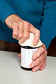 Elderly woman opening a bottle