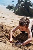 Boy playing in sand at the beach