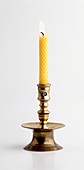 Lit beeswax candle in brass candle holder