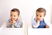 Twin baby boys playing with spoons