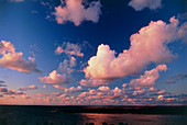 Fair-weather cumulus clouds over water at sunset