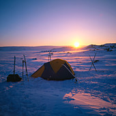 Twilight view of a campsite on snow-covered ground