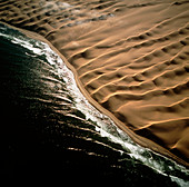 View of Namib desert dunes meeting the ocean