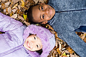 Smiling children lying on autumn leaves