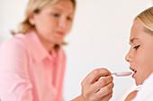 Mother giving daughter medicine