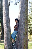 Teenager leaning against a tree