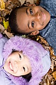 Smiling children lying on autumn leaves