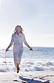 Senior woman skipping on a beach