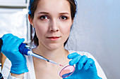 Woman holding pipette and petri dish