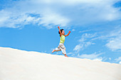 Young boy running on sand dunes