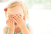 Young girl covering face with hands