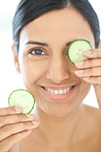 Woman holding slices of cucumber