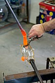 Glassblower cuts molten glass into shape