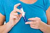 Woman using a finger pricker