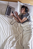 Man in bed with laptop and phone
