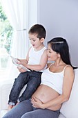 Pregnant woman with son reading book