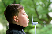 Boy blowing miniature wind turbine