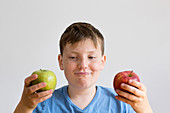 Boy holding red and green apple