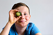 Boy holding cucumber over eye