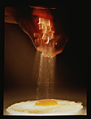Sprinkling salt onto a fried egg