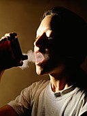 Young woman using aerosol inhaler for asthma