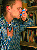Young man using an aerosol inhaler for asthma
